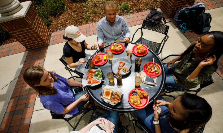 People sitting at a round table eating and talking. 